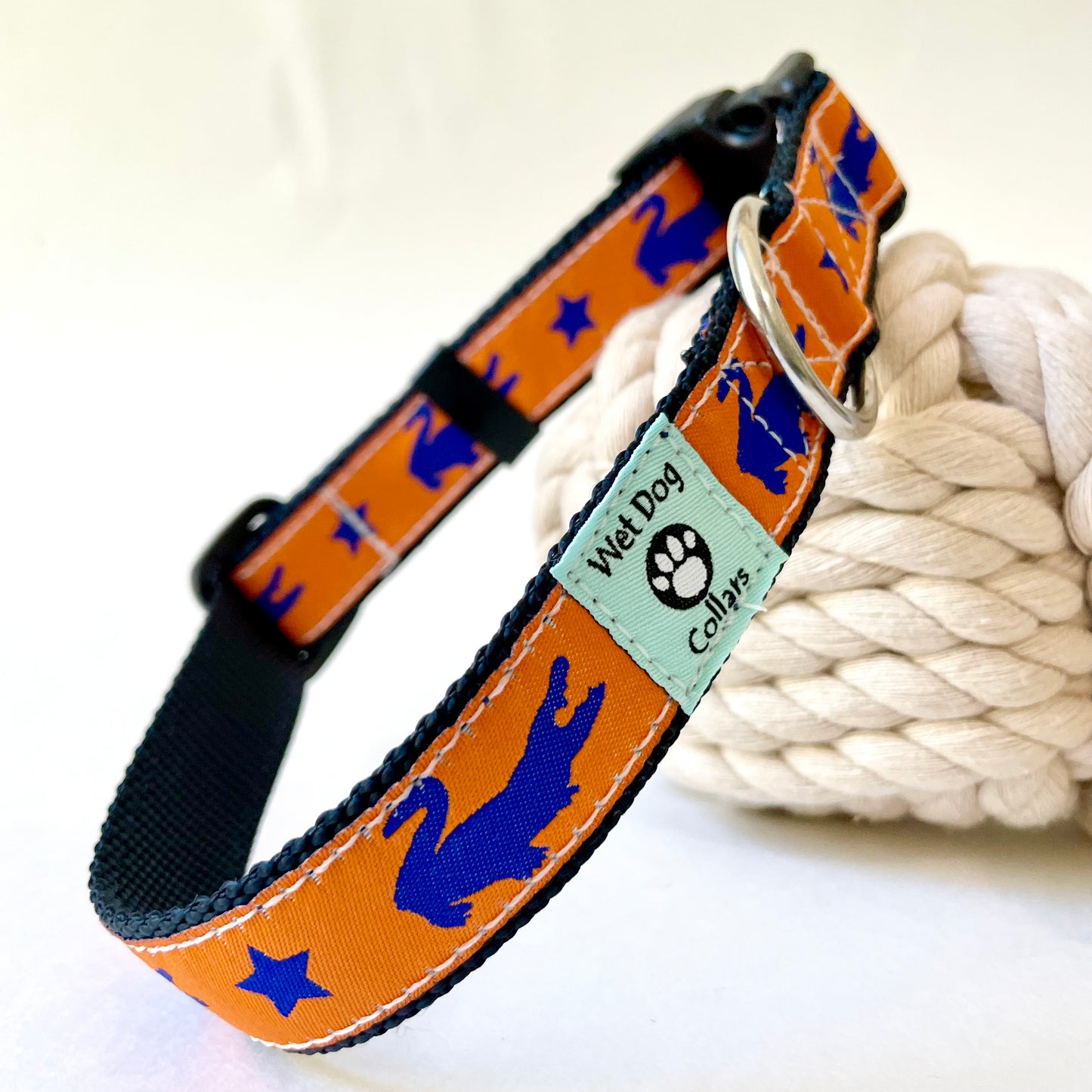 Dog collar with blue gator and star design on an orange background, featuring Wet Dog Collars brand tag