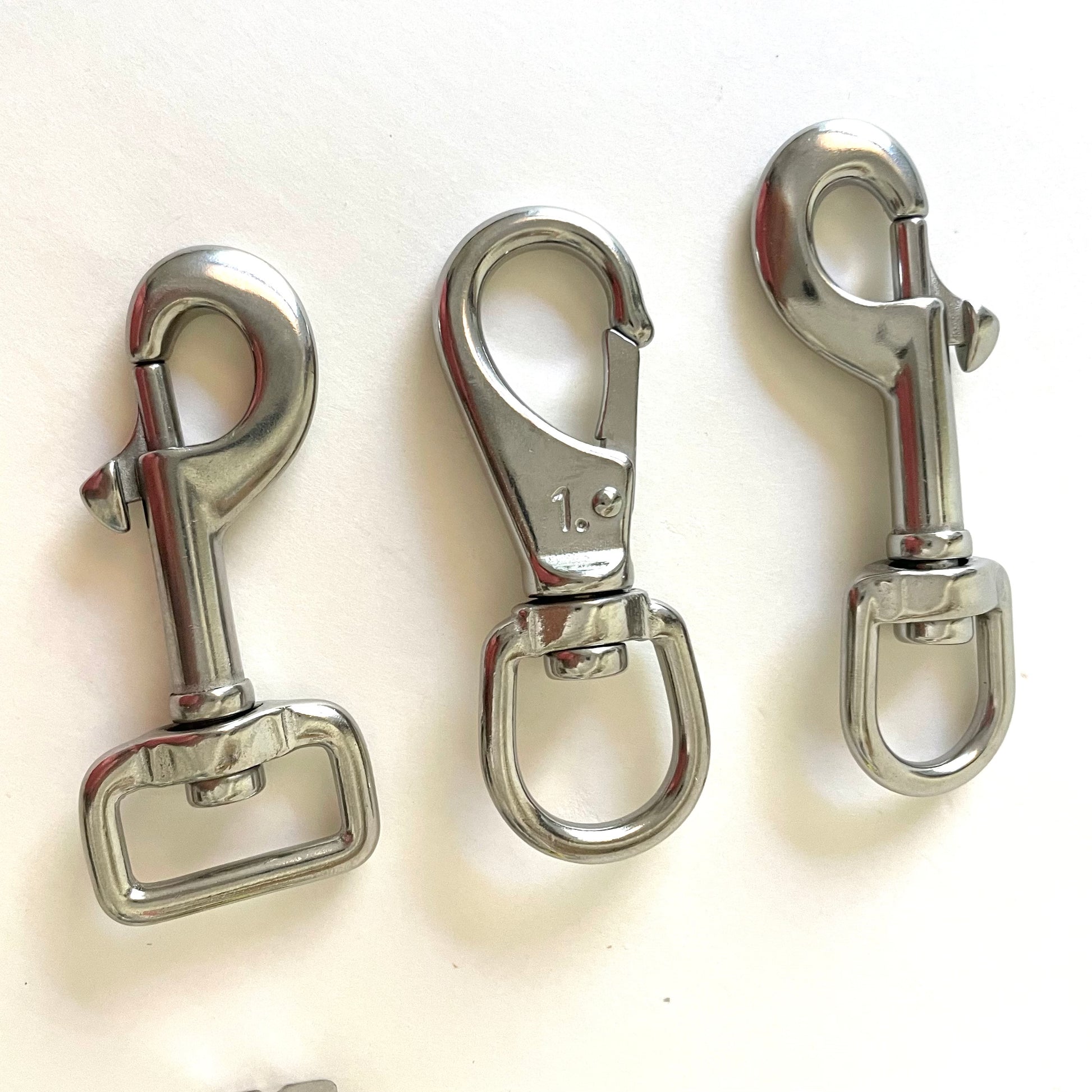 Three stainless steel metal swivel hooks on a white background