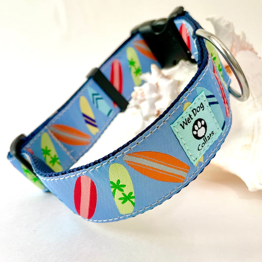 A blue fabric dog collar with a colorful surfboard pattern, featuring a rust proof D-ring