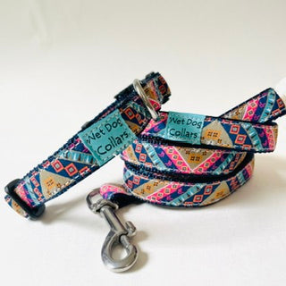 A patterned dog collar and matching leash with a stainless clasp, displayed on a plain white background. The fabric features a colorful geometric tribal-style print with blue, pink, orange, and yellow, and has a light blue woven label that reads 'Wet Dog Collars'.