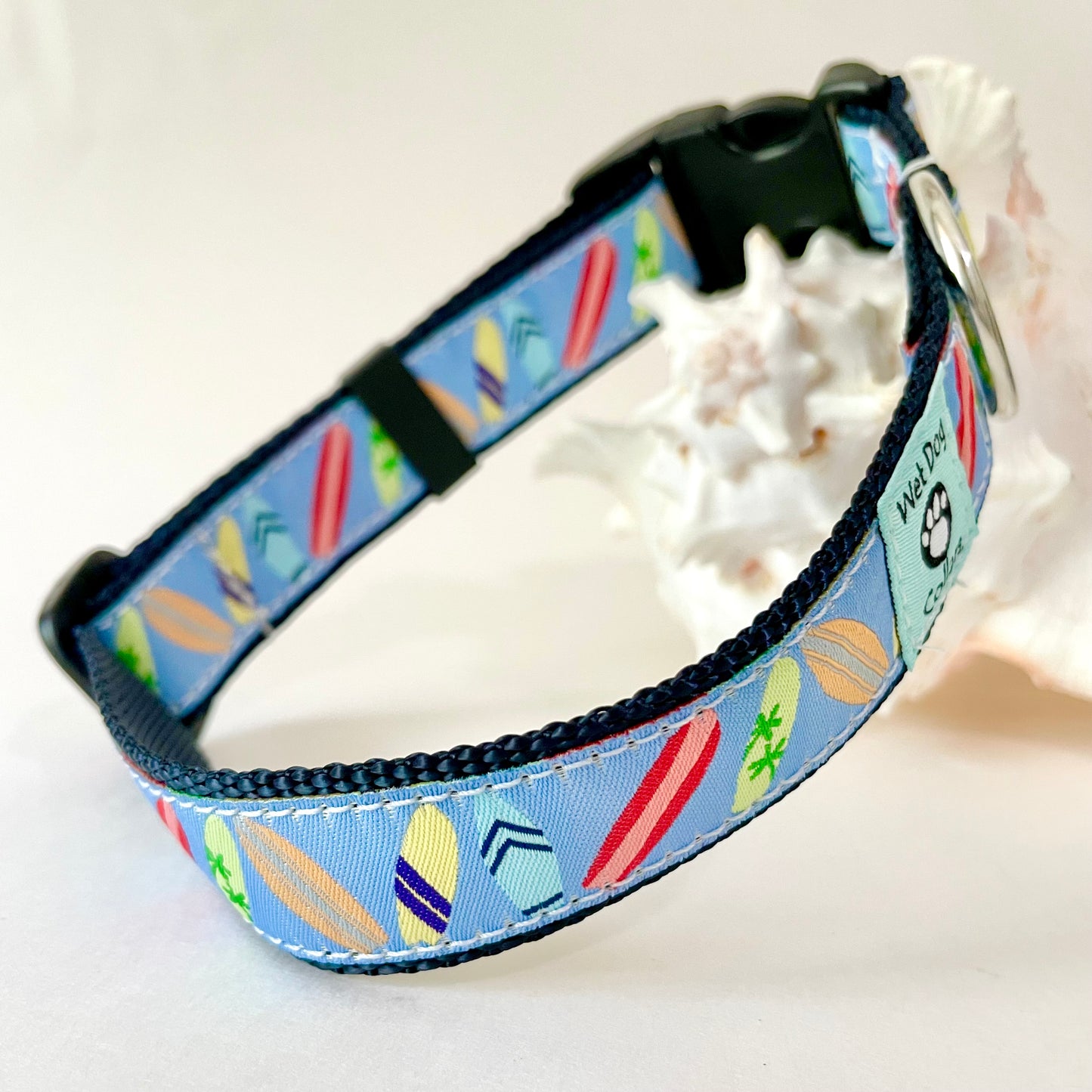 A pet collar with a light blue background and a colorful surfboard pattern with rust proof metal for beach