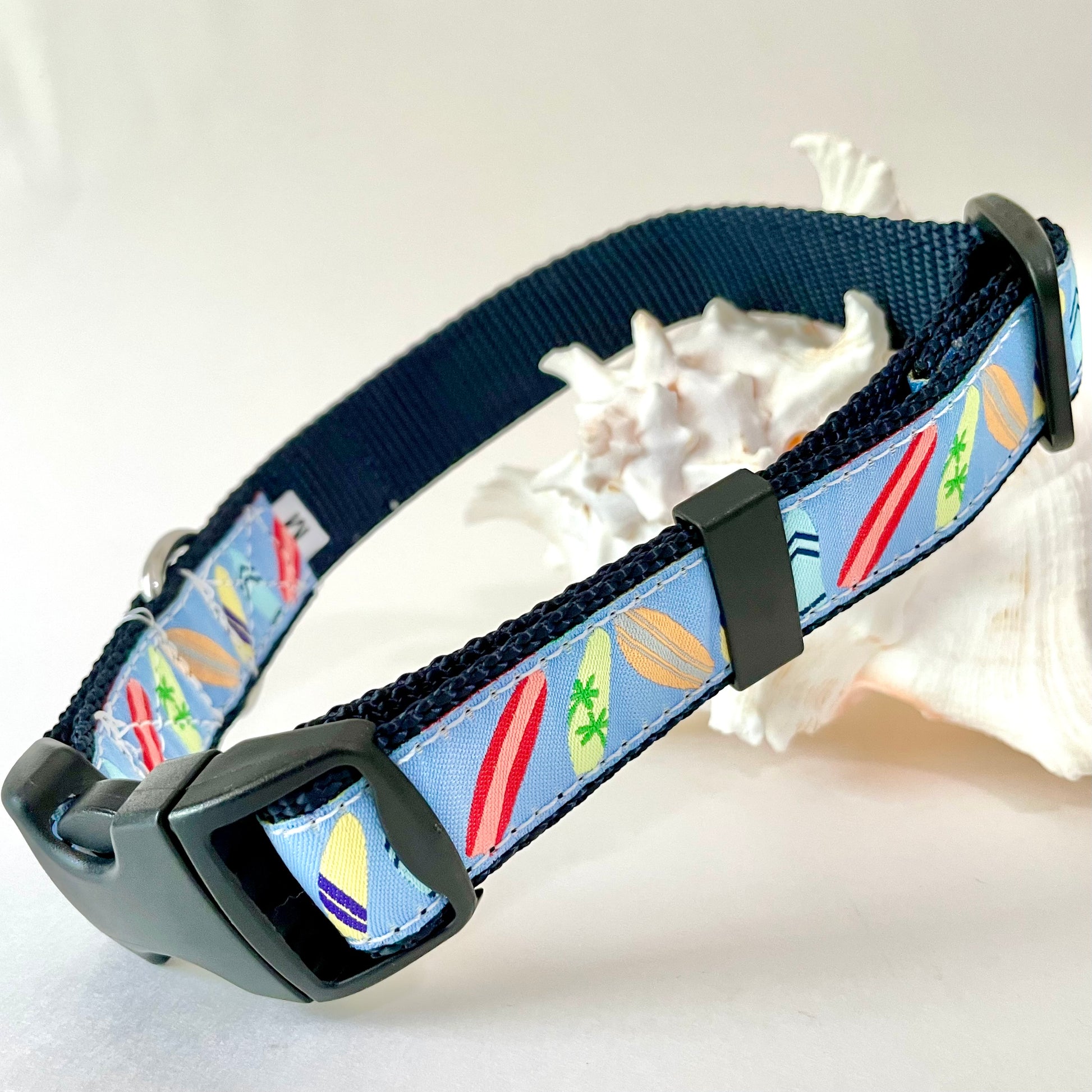 A blue fabric dog collar with a colorful surfboard pattern,  brand 'Wet Dog Collars' and rust proof D-ring